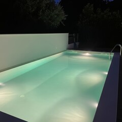 A serene and inviting swimming pool illuminated at night with surrounding greenery.