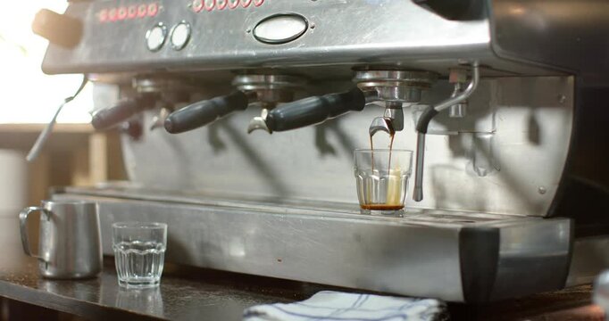 Hand is placing shot glass as machine is pulling double shot to fill glass at counter
