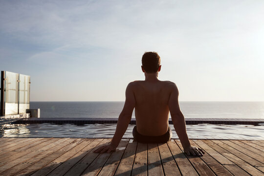 man sitting near swimming pool, beach holidays, solo travel