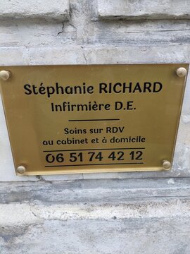 Saintes, France - January 28, 2026: Brass nameplate for nurse Stephanie Richard with contact information displayed on a stone wall in a residential area