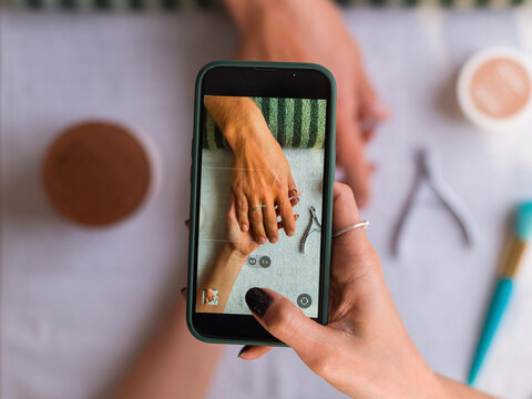 Manicurist taking picture of client hand 