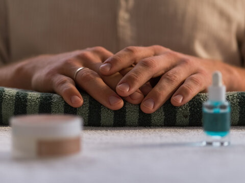 Hands Resting on a Towel With Nail Care Products in a Serene Setting