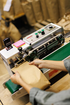 Partial top view of female worker packing package with coffee beans