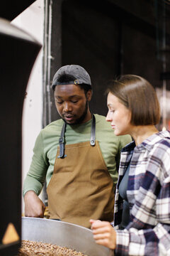 Young concentrated workers controlling process of coffee roasting