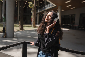 Obraz premium Young woman enjoying music with headphones outdoors closing eyes