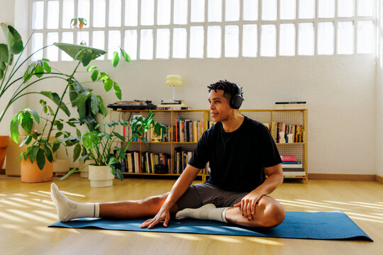 Man stretching and listening to music at home
