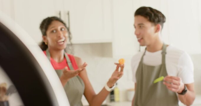 Cooks wearing aprons pulling into focus in kitchen by ring light, filming orange bite on spoon