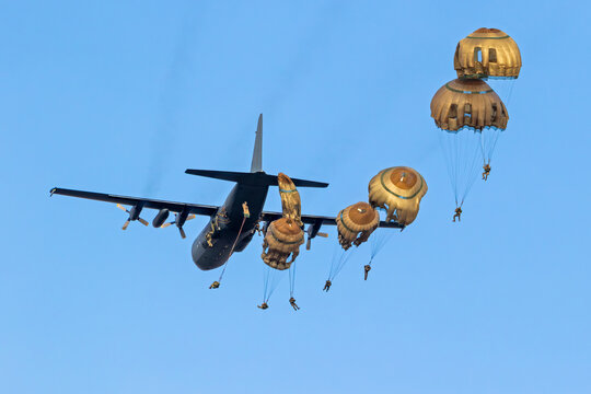 Military parachutist paratroopers parachute jumping out of an air force plane.