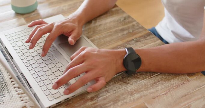 Hands are typing on laptop on table with mug after landing on keys, finishing work