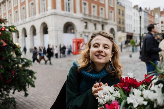 Happy woman smiling near Christmas cyclamen flowers in Covent Garden
