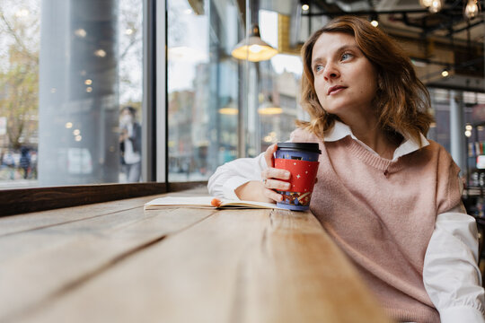 Woman drinking coffee in cafe looking out window