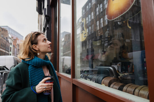 Woman window shopping for guitars in London music store