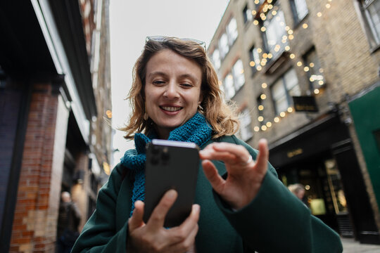 Woman smiling and using smartphone on London street