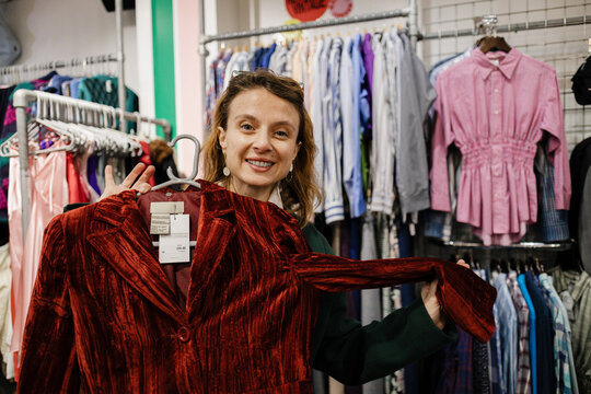 Woman holding vintage velvet jacket in thrift store