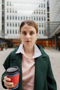 Woman holding coffee cup outdoors in business district