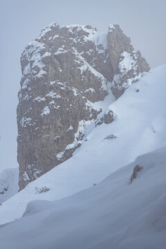 Dramatic winter view of Grignetta spires emerging from thick fog and low clouds. Moody alpine landscape with snow-covered rocky peaks in the Grigne mountains, Lecco, Italy - January 2026