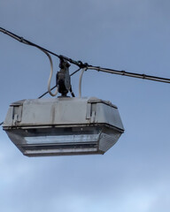 Street light hangs from wire in urban area under cloudy sky during late afternoon