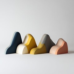 Four colorful, abstract, mountain-like forms on a white surface, side by side