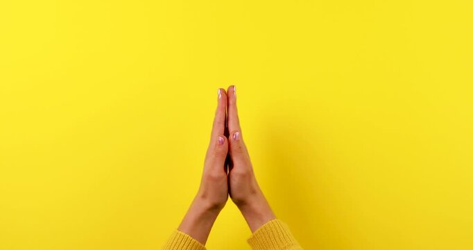 Close-up of hands clapping against a bright yellow background. Symbol of applause, approval, celebration, and success. Simple expressive gesture with copy space. Isolated, high contrast, 4K video.