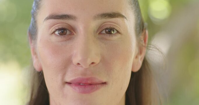 Woman starting neutral shifting into wide laughing smile under trees dappled light hair pulled back