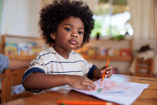 Young child drawing with crayon at table.