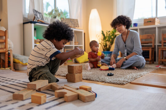 Children play with blocks, supervised by a caregiver.