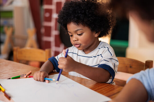 Young child drawing with crayons at a table.