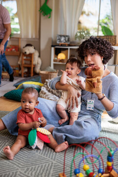 Caregiver entertains two babies with a puppet show.