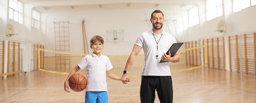 Pe teacher and young male student posing in a school gymnasium