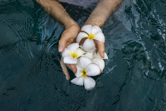 purity, water ritual with flowers, female hands with white flowers