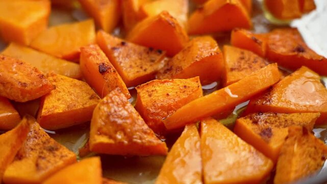 Roasted pumpkin pieces sprinkled with cinnamon in a glass container