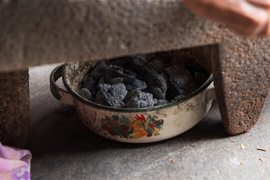 Bowl filled with charcoal beneath a metate for cacao grinding