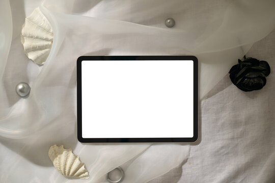 A modern tablet with a blank screen is set on a stylish fabric surface