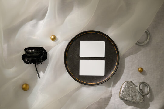 A minimalist still life featuring blank cards and a black flower