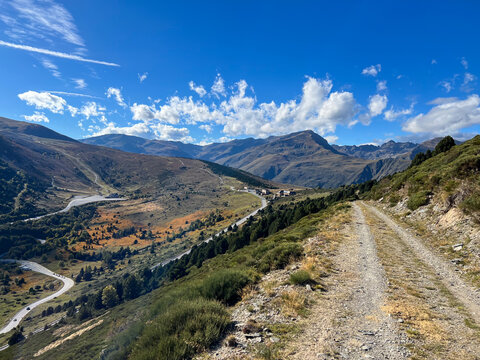 Dirt track winding through Porte Puymorens valley under blue sky