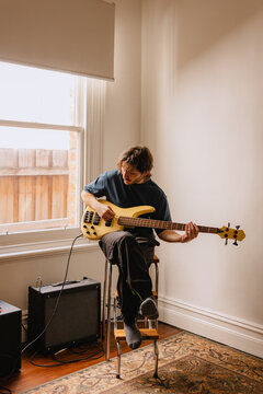 Young man plays a yellow bass guitar 