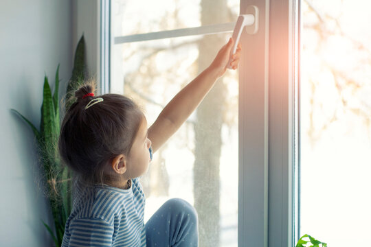 Little girl opens the window. Children safety at home. Prevention of falling accident