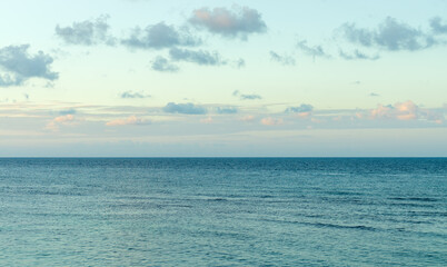 Ocean water against blue sky white morning clouds