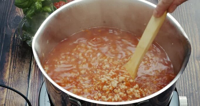Chef stirring rich Bolognese sauce, showcasing Italian cuisine, culinary skills, and gourmet food preparation in a professional kitchen.