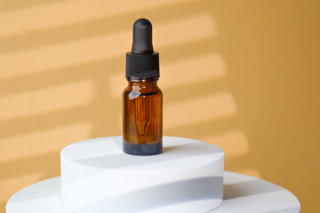 Amber glass serum dropper bottle on beige stone pedestal