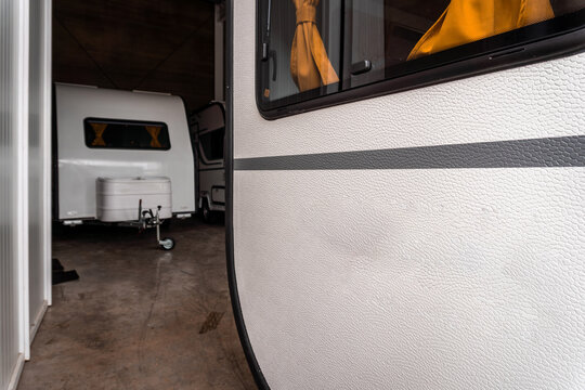 Caravan side wall and window detail showing numerous dents from hail damage while stored inside a garage