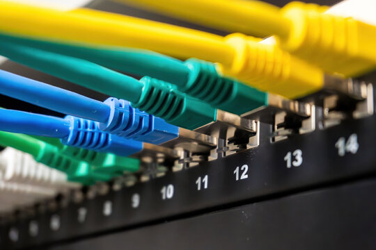 Colorful ethernet cables plugging into a numbered network switch, creating essential data and internet connectivity for it infrastructure