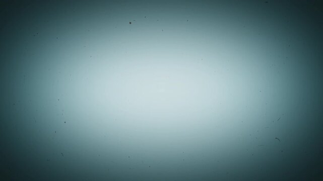 Simulating aged cinema, this clip displays a flickering, cool-toned background marred by dancing black dust specks, scratches, and a heavy vignette, evoking a retro film aesthetic