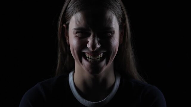4K cinematic dark portrait of young woman laughing creepily with evil expression in dramatic lighting