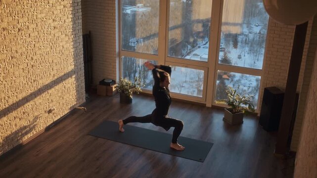 Calm man holds deep forward fold on mat by tall window in studio
