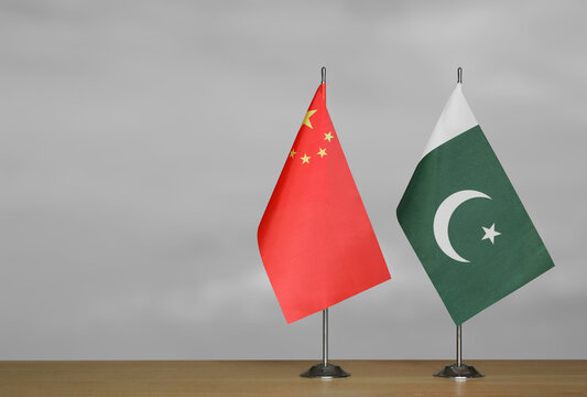 Two table flags of the China and Pakistan on a blurred gray background