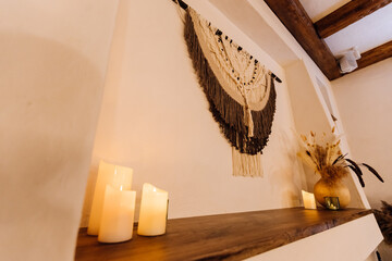 Obraz premium Boho macrame wall hanging with candles and dried flowers on rustic shelf