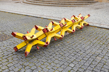Portable anti-vehicle barriers known as Czech hedgehogs blocking road access on urban square. Temporary metal roadblocks for security, traffic control, military or civil defense concept © Vlad Yakubovskiy