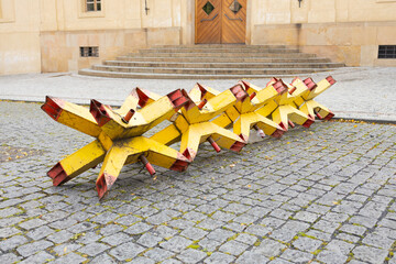 Portable anti-vehicle barriers known as Czech hedgehogs blocking road access on urban square. Temporary metal roadblocks for security, traffic control, military or civil defense concept © Vlad Yakubovskiy