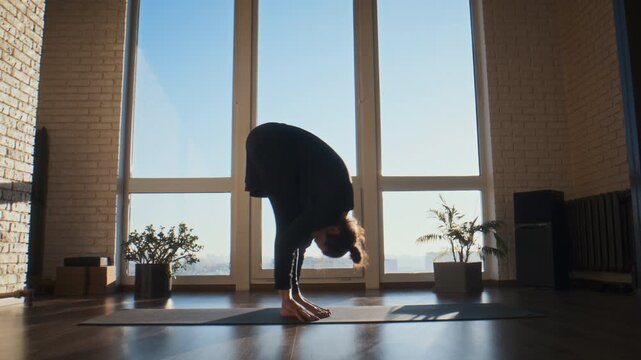 Joyful man bends into standing backbend on yoga mat in studio